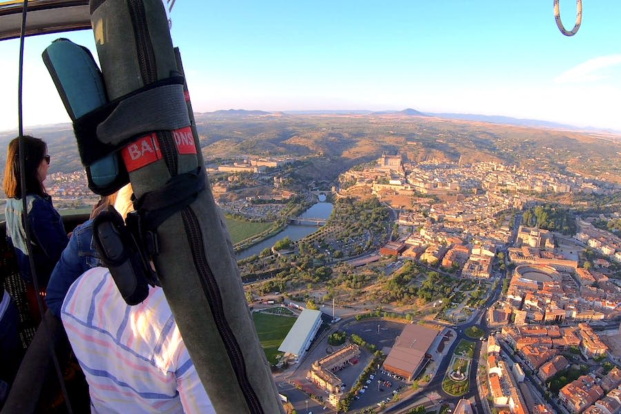 열기구에서 찍은 강이 흐르는 도시의 공중 풍경. 건물, 도로, 먼 언덕이 보이는 풍경입니다.