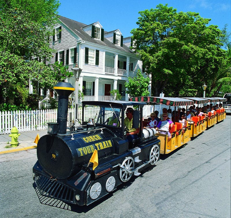 관광객들은 초록색 셔터와 피켓 울타리가 있는 하얀 집을 지나 '골든 투어 트레인' 이라는 이름의 검은색과 노란색의 작은 기차를 탄다.