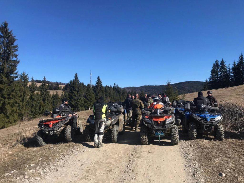 맑은 하늘과 상록수를 배경으로 ATV를 든 사람들이 언덕의 흙길에 모였습니다.