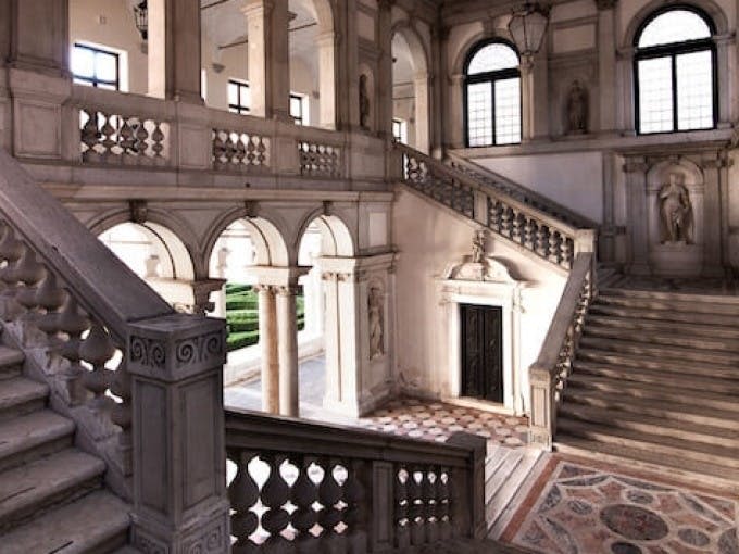 아치형 출입구, 대리석 기둥, 커다란 창문이 있는 상층부로 이어지는 웅장한 계단이 있는 화려한 인테리어.