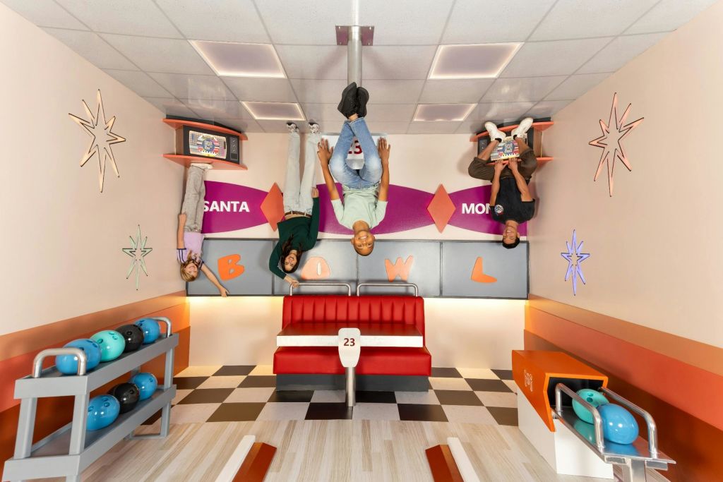 복고풍 인테리어가 돋보이는 볼링장에 4명이 거꾸로 매달려 있는 듯한 착각을 불러일으킵니다.