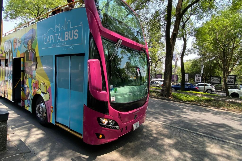 멕시코시티의 '캐피탈 버스' 라고 적힌 2층 투어 버스가 가로수 길에 주차되어 있습니다.