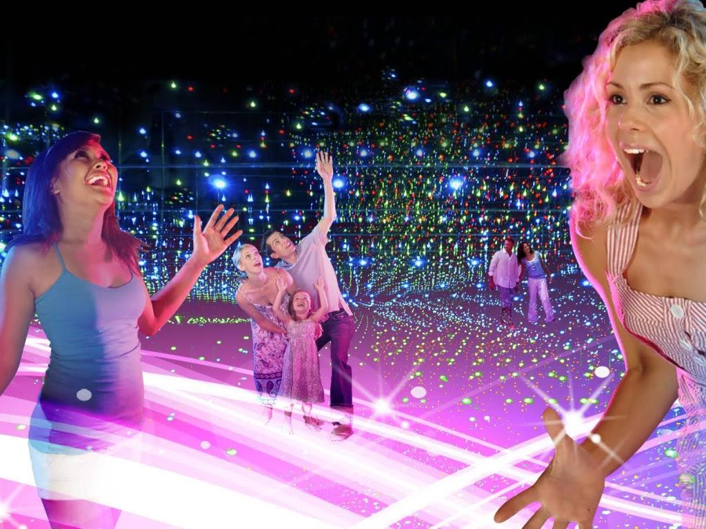 어두운 방에서 활기차고 화려한 조명 디스플레이를 즐기는 사람들은 분홍색 빛과 다채로운 점들이 현장을 비춥니다.