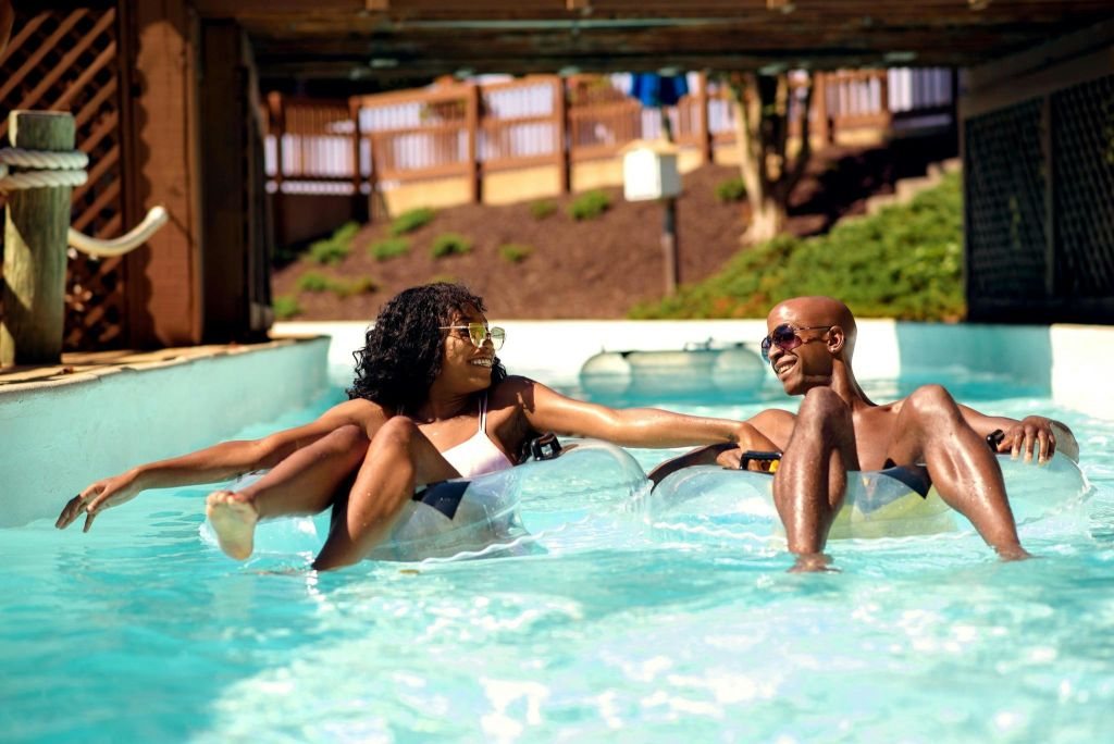 워터파크의 나른한 강가에서 이너튜브에 떠 있는 남녀가 서로에게 미소를 짓고 있습니다.