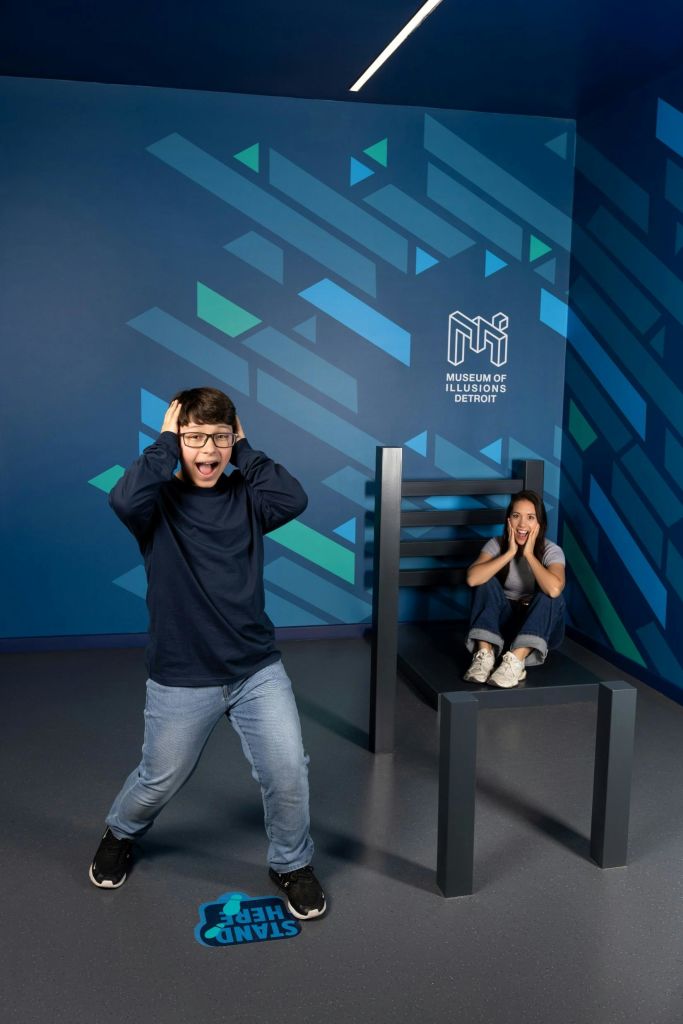 디트로이트 환상 박물관의 광학 착시실에 있는 두 사람이 대형 가구와 상호 작용하는 것처럼 보입니다.