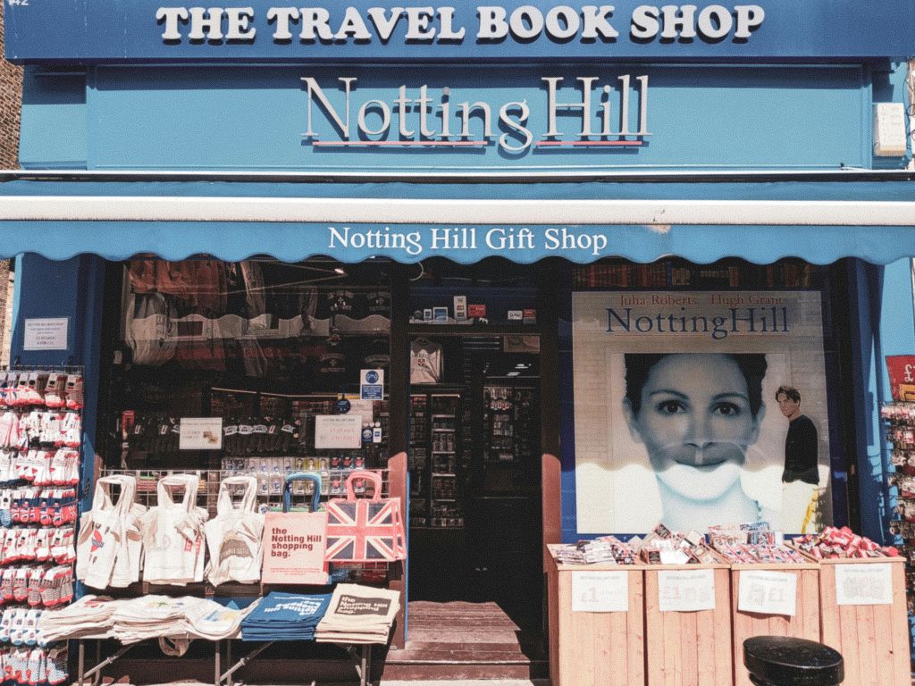 가방, 책, 대형 "노팅힐" 영화 포스터가 있는 "The Travel Book Shop" 과 "Notting Hill Gift Shop" 매장.