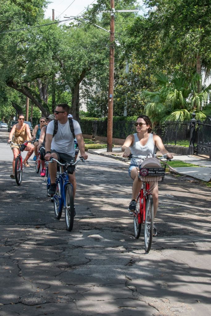 화창한 날 나무가 늘어선 거리에서 자전거를 타는 사람들의 모임.