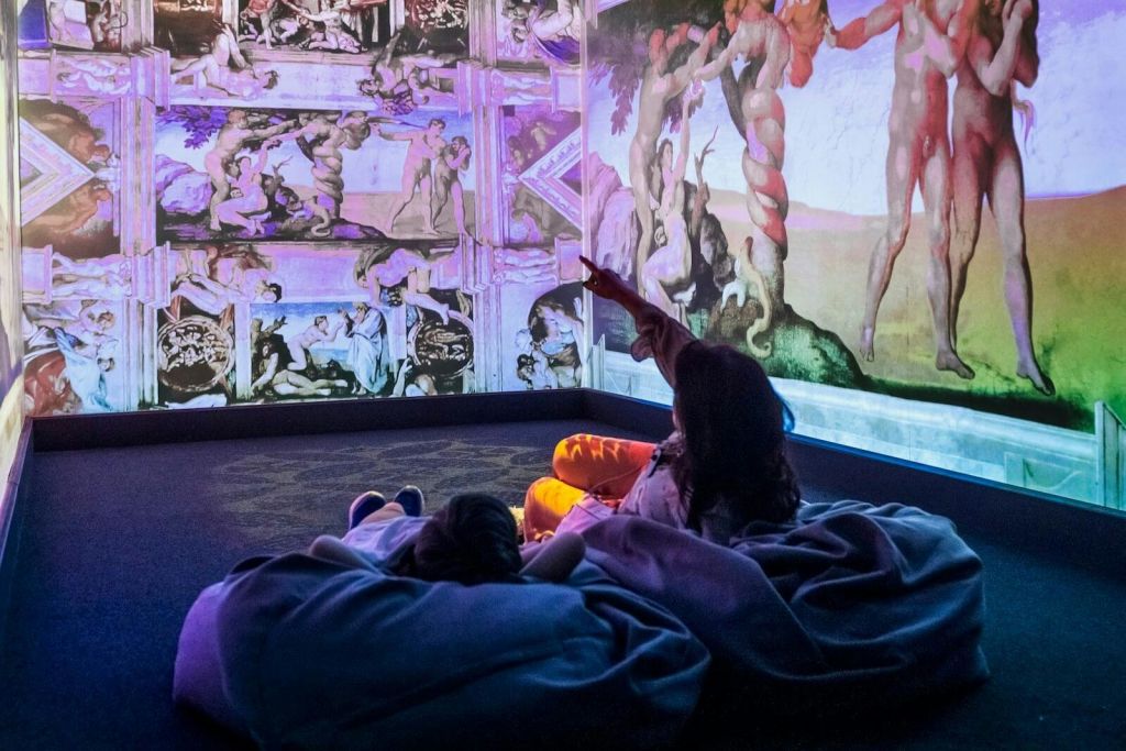 이탈리아 르네상스 콘텐츠가 가득한 몰입형 프로젝션 룸에서 빈백에 누워 있는 두 사람