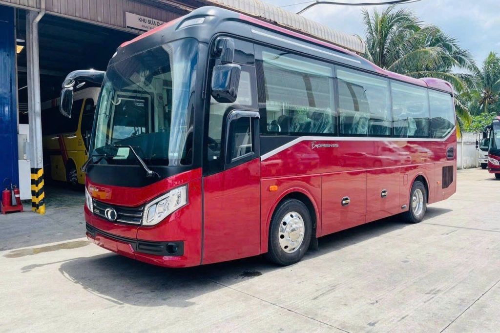 건물과 야자수 근처의 콘크리트 표면에 빨간색 투어 버스가 주차되어 있습니다.