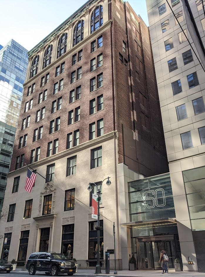 미국 국기가 그려진 벽돌 건물로, 현대적인 유리와 석조 건물이 인접해 있으며 350이라는 숫자가 적힌 표지판이 있습니다.