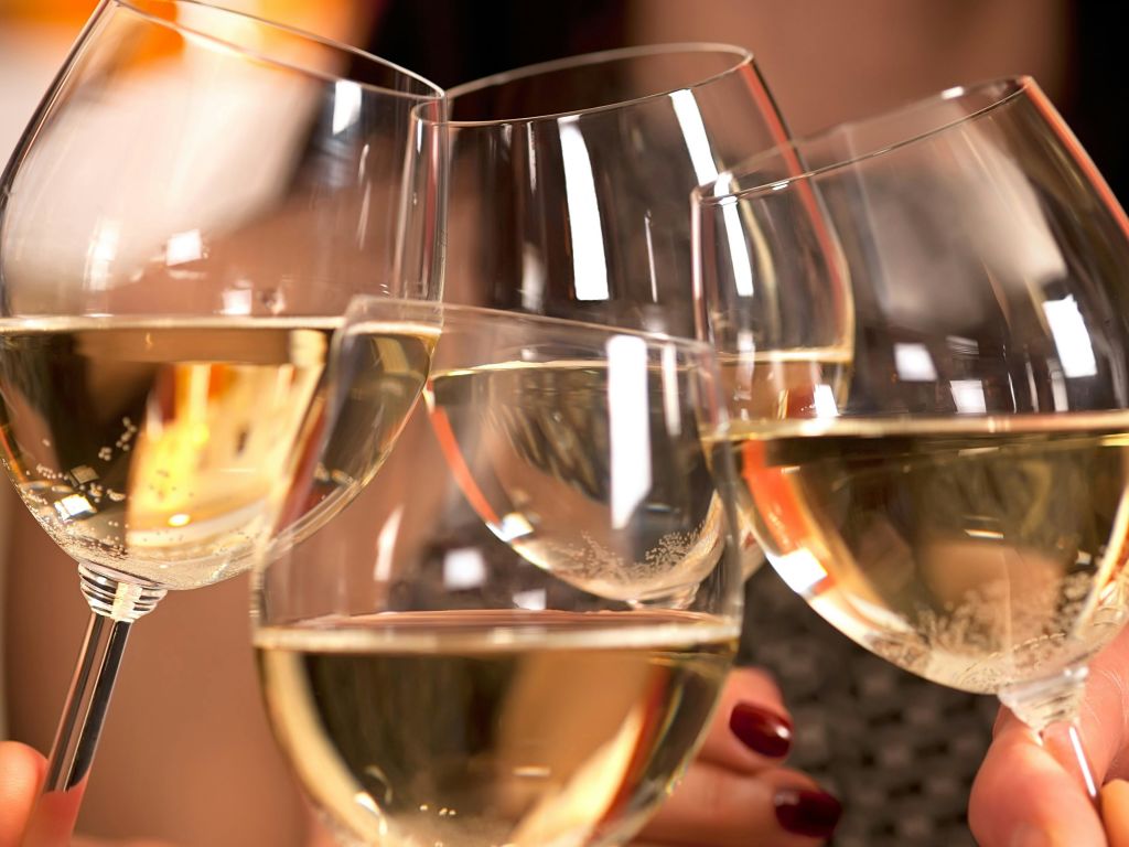 축하용 토스트에 화이트 와인이 담긴 와인잔 네 개가 함께 찰칵찰칵 거리는 클로즈업 사진.