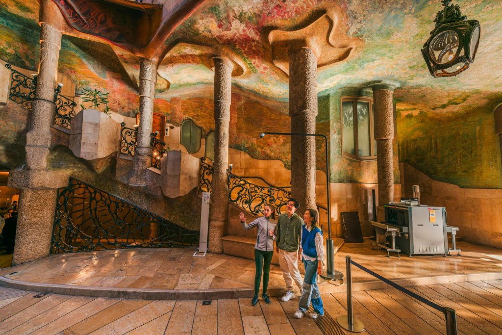 화려한 천장, 석조 기둥, 정교한 철공예품으로 화려하게 디자인된 인테리어에 세 사람이 서 있습니다.