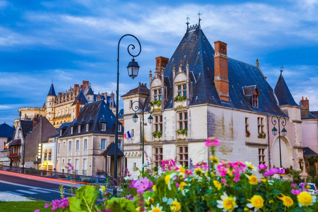 화려한 꽃과 빈티지 가로등으로 둘러싸인 가파른 지붕과 굴뚝이 있는 유럽풍 건물.