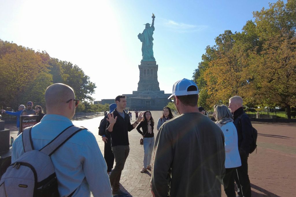 장엄한 자유의 여신상을 배경으로 엘리스 섬 투어 그룹의 매혹적인 사진.