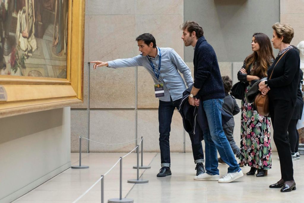 두 남자가 박물관에서 커다란 액자 그림을 자세히 살펴보고 있는데, 한 남자는 가리키고 다른 한 남자는 앞으로 기울어져 있습니다.