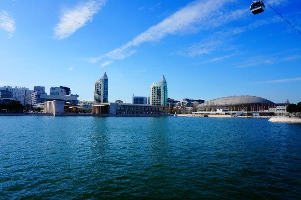 현대적인 건물이 있는 도시 풍경과 맑고 푸른 하늘 아래 푸른 물줄기를 가로질러 바라보는 돔형 구조물.