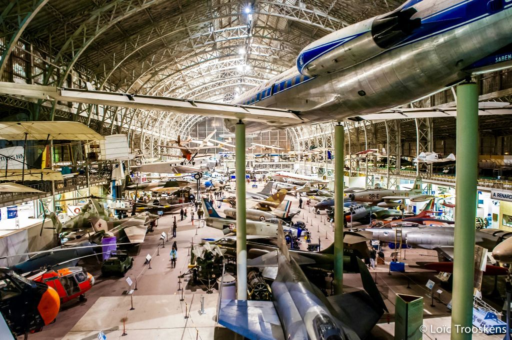 다양한 항공기가 바닥에 전시되어 있고 천장에 매달려 있는 대형 실내 항공 박물관, 사람들이 돌아다닙니다.