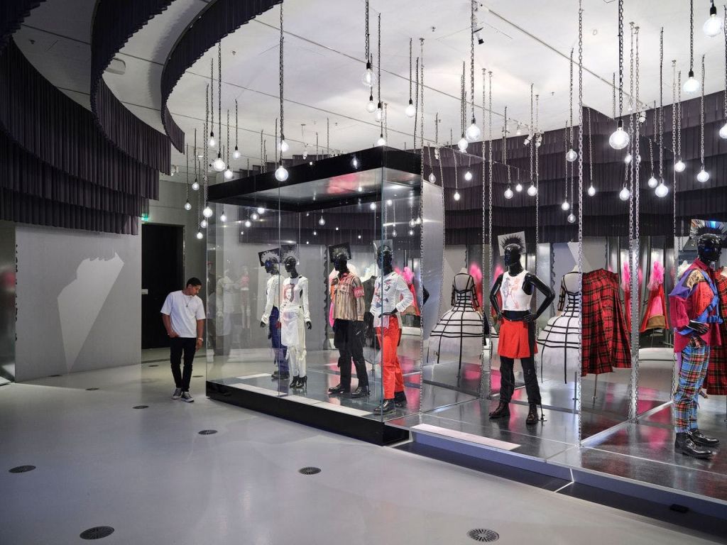 유리 디스플레이 내부에서 다양한 의상을 입은 마네킹이 관찰되는 현대적인 패션 전시회입니다.