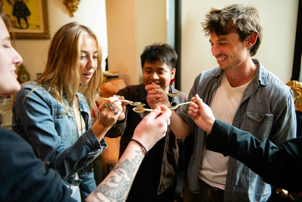 한 무리의 사람들이 실내에서 얽힌 은수저를 들고 웃으며 상호작용하고 있습니다.