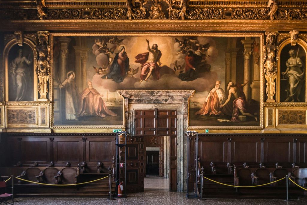 나무 벤치가 있는 화려한 홀, 성경의 장면을 묘사한 커다란 벽화, 나무 출입구가 있습니다. 문 근처에서 볼 수 있는 소화기.