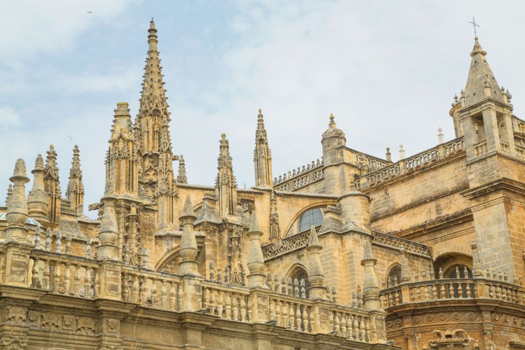 높은 첨탑, 뾰족한 아치, 흐린 하늘 아래 복잡한 석조 작품이 있는 유서 깊은 대성당의 고딕 양식 건축 디테일.