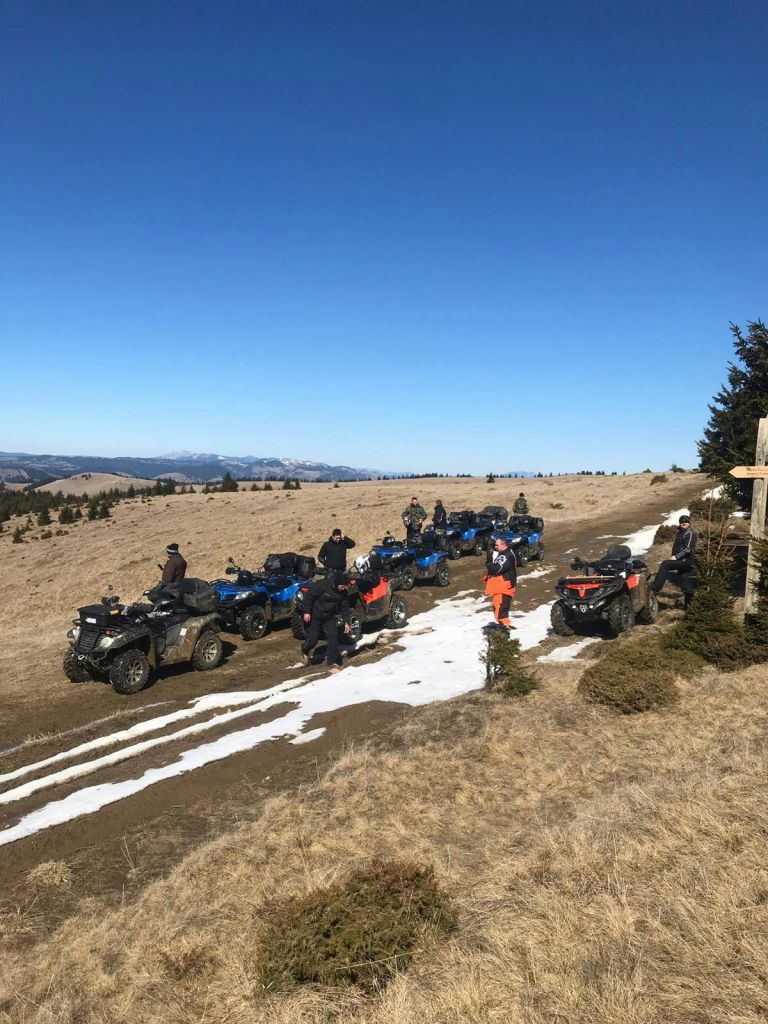 산과 맑고 푸른 하늘을 배경으로 잔디가 우거진 부분적으로 눈이 쌓인 언덕에 ATV를 설치한 사람들의 모임.
