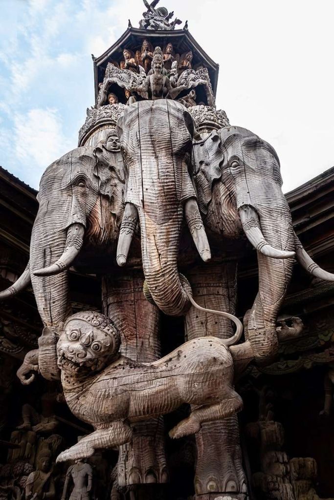화려한 건축 구조의 일부인 세 마리의 코끼리와 신화적인 생물이 특징인 정교한 목조 조각품.