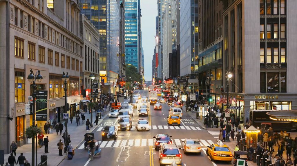 저녁에는 자동차, 택시, 보행자가 다니는 번화가로, 높은 건물과 조명으로 둘러싸여 있습니다.