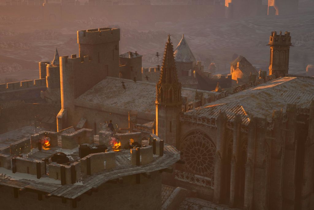 작은 불 주위에 사람들의 그룹과 함께 석양에 중세 성 지붕. 고딕 양식의 건축물과 첨탑이 보입니다.