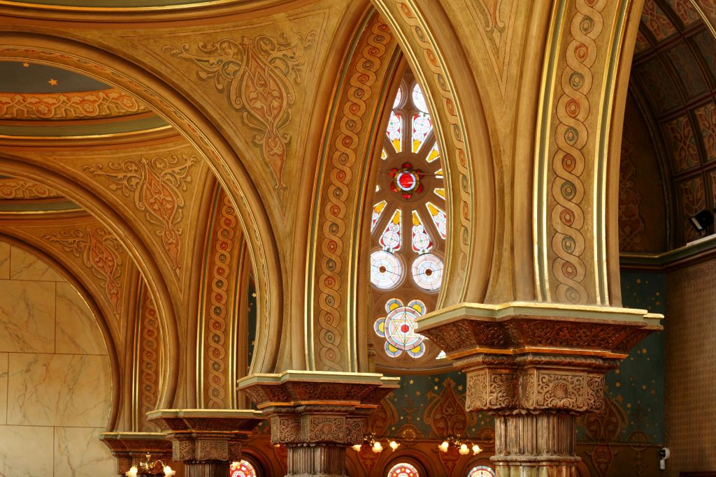 정교한 디자인의 화려한 아치형 통로와 기둥, 기하학적인 패턴이 돋보이는 스테인드글라스 창이 장식되어 있습니다.