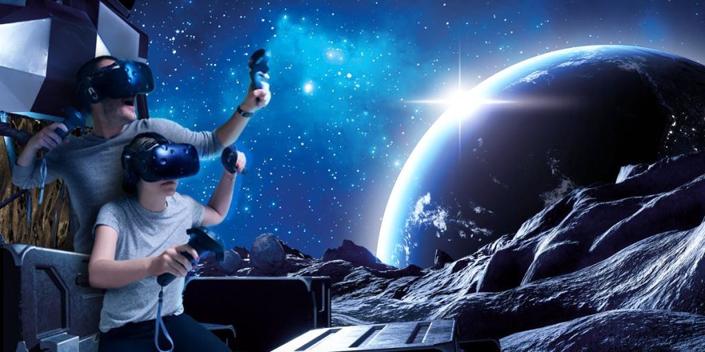 VR 헤드셋을 착용하고 컨트롤러를 들고 있는 두 사람은 별, 행성 및 암석 지형이 있는 우주 테마 시뮬레이션에 몰입합니다.