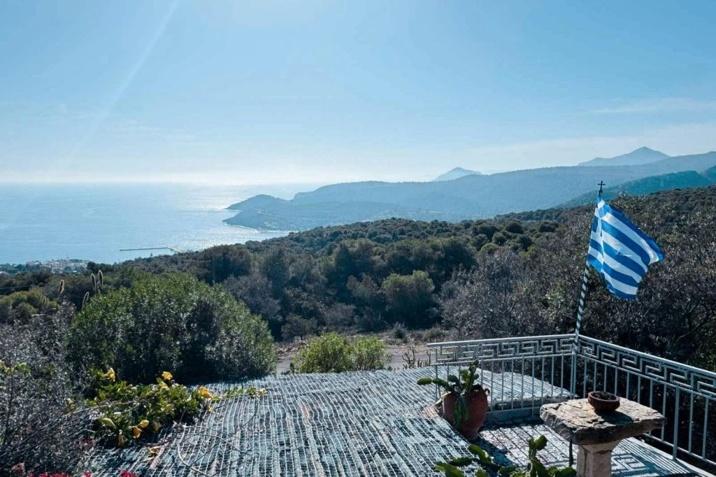 맑고 푸른 하늘 아래 언덕, 잔잔한 바다, 화분이 있는 테라스가 있는 아름다운 해안 전망.