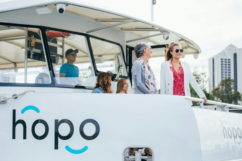 '오포' 가 옆으로 보이는 배의 갑판에 여러 사람이 서 있습니다. 두 여성이 웃으며 이야기하고 있습니다.