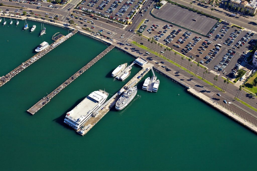 선착장, 여러 개의 계류 보트, 차량으로 가득 찬 인접한 주차장이 있는 정박지의 공중 전망.