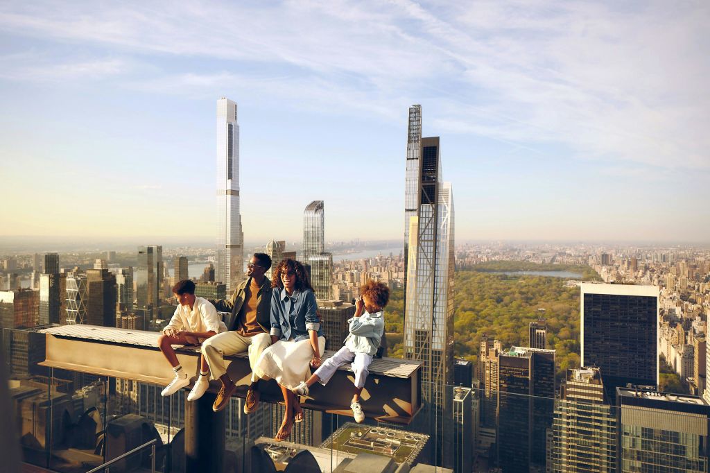 높은 건물과 공원이 있는 도시 풍경이 내려다보이는 하이빔에 네 명이 앉아 있습니다.