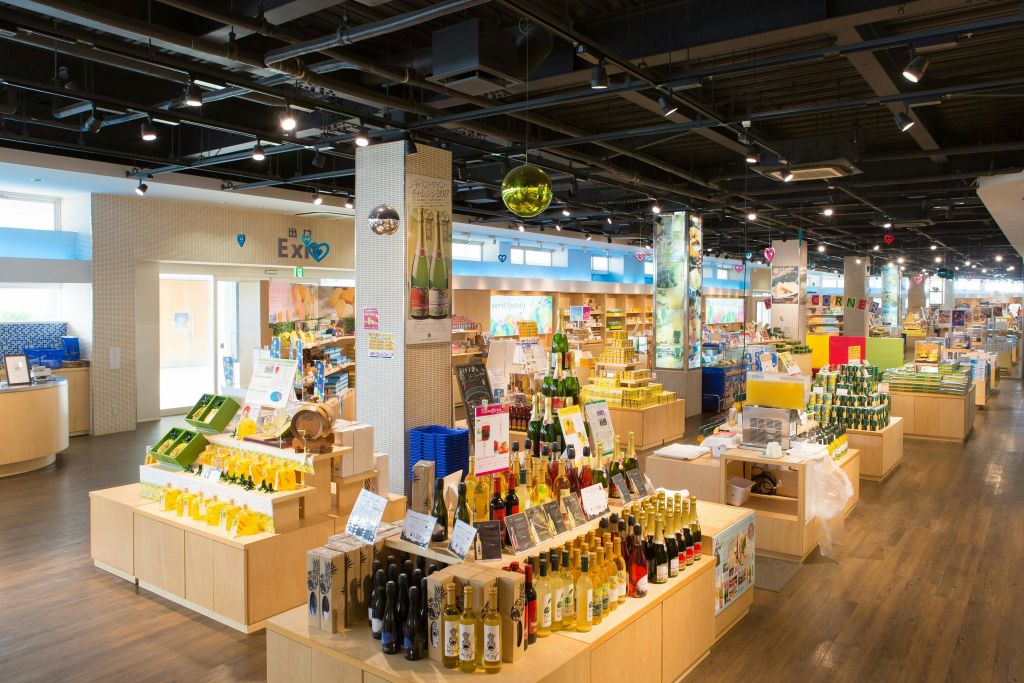 깔끔하게 정리된 와인병과 다양한 제품이 진열대와 테이블에 진열된 조명이 좋은 현대적인 매장 인테리어.