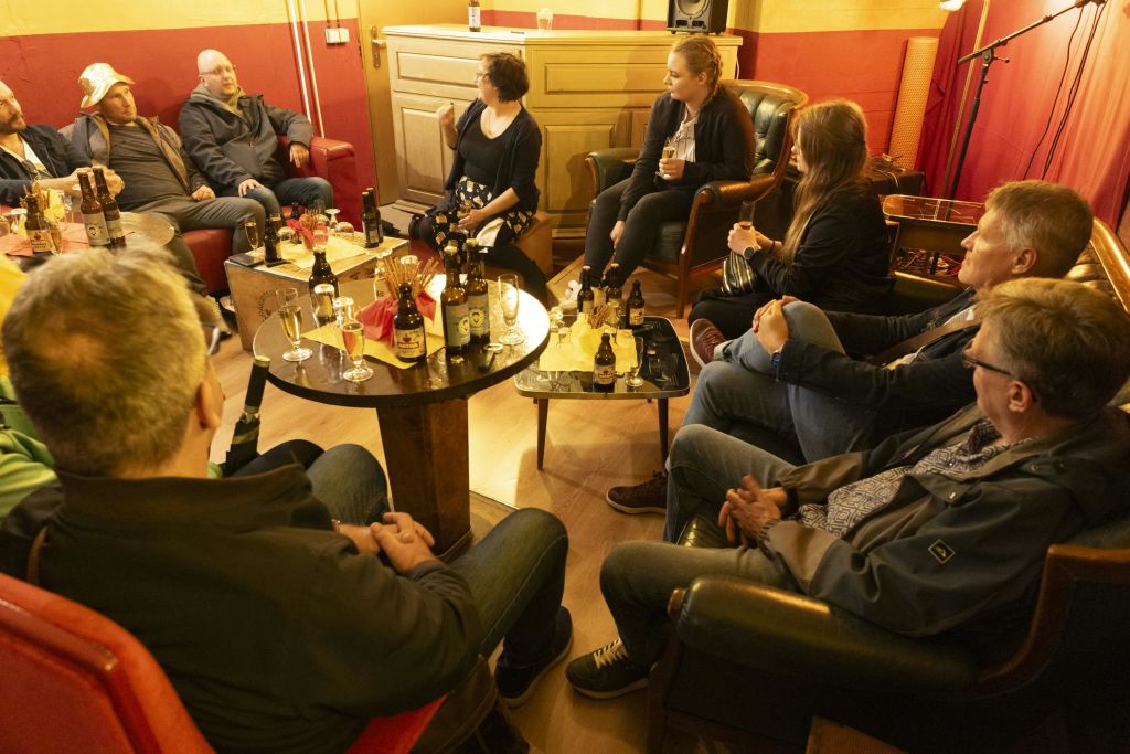 아늑한 방에 앉아 수다를 떨고 술을 마시는 사람들, 병과 유리잔이 놓인 테이블.