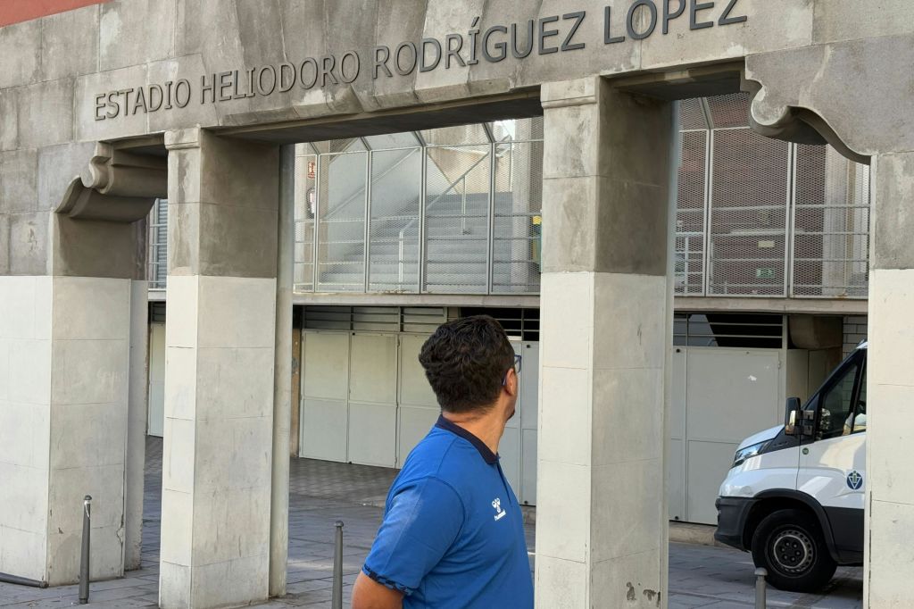 파란색 셔츠를 입은 사람이 위의 "Heliodoro Rodríguez López" 라는 글자와 함께 콘크리트 구조물을 올려다보고 있습니다.