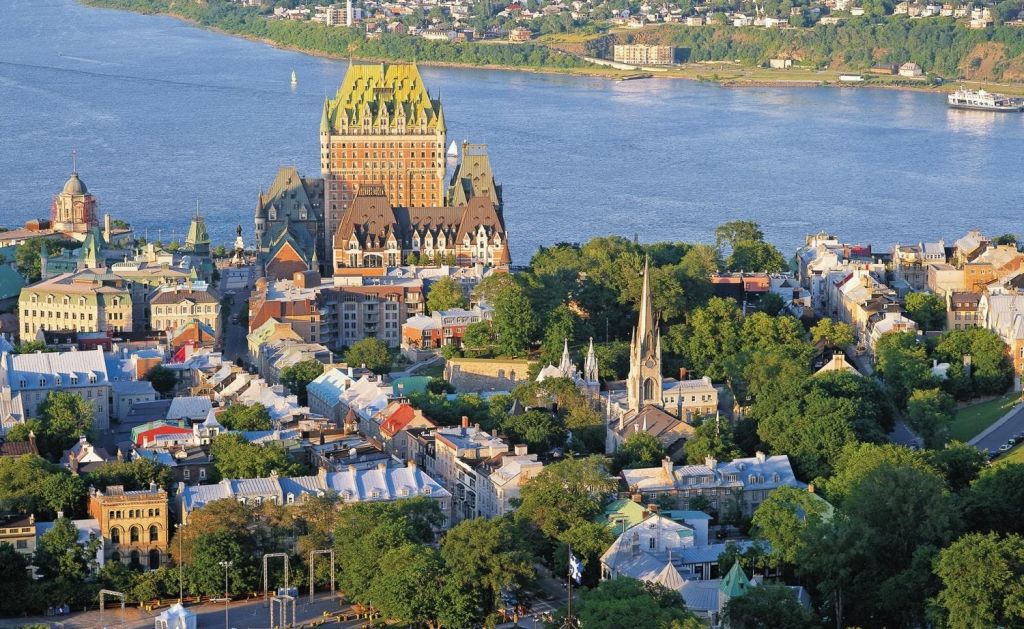 거대한 역사적 건물, 높은 첨탑이 있는 교회, 녹지와 강으로 둘러싸인 주택이 있는 도시의 공중 전망.