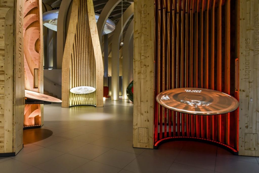 조명이 희미한 방에 목조 구조물과 조명 원형 디스플레이가 있는 현대적인 박물관 전시관이 있습니다.