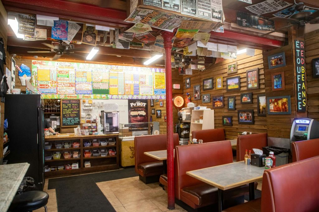 빨간 부스, 메뉴판, 화려한 인테리어가 돋보이는 아늑한 다이너 인테리어로 벽에 걸린 전단지와 액자 그림이 특징입니다.