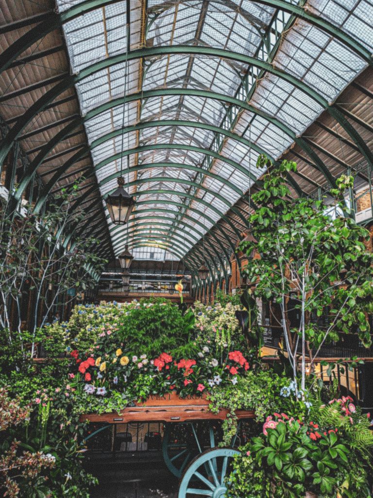 커다란 아치형 유리 지붕 아래에는 풍부한 꽃 식물, 나무, 매달린 가로등이 있는 실내 정원이 있습니다.