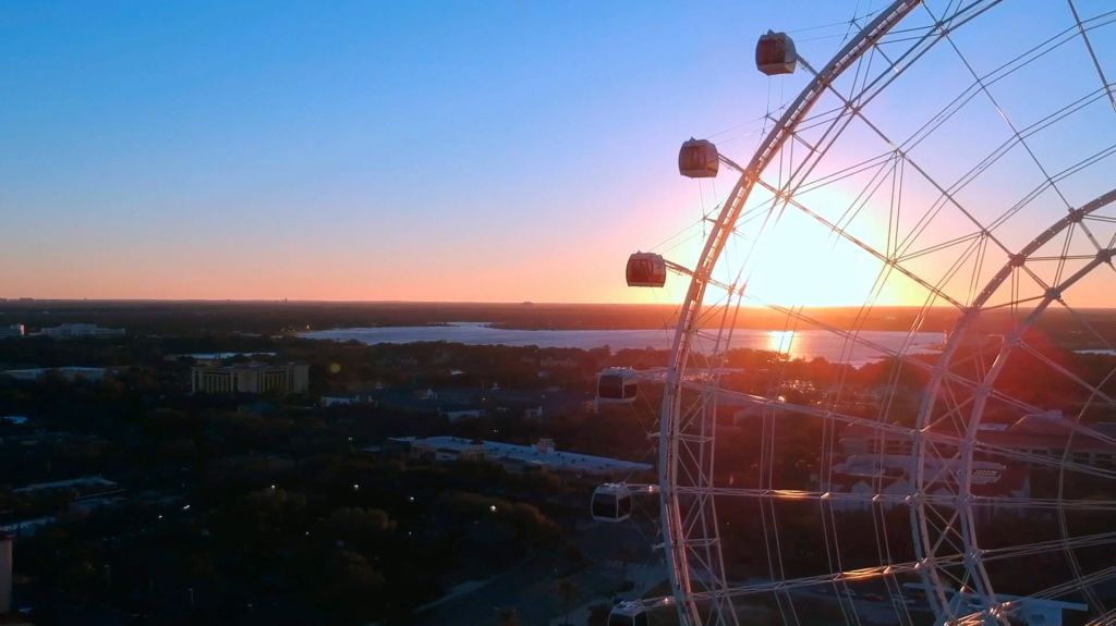 호수와 도시 풍경이 내려다보이는 석양에 동봉된 통나무집이 있는 대형 대관람차.