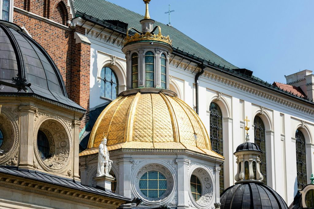 맑고 푸른 하늘 아래 정교한 건축물과 주변 구조물이 있는 황금 돔형 건물입니다.