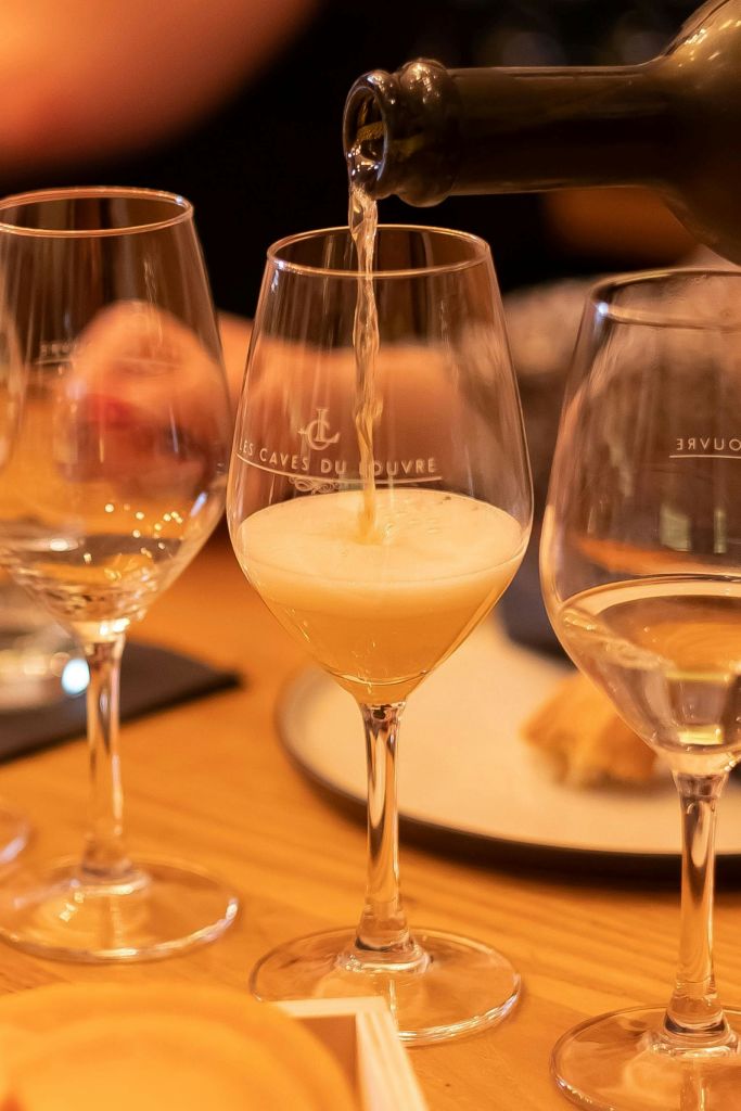 나무 테이블 위에 다른 빈 와인 잔으로 둘러싸인 스파클링 와인 한 잔이 쏟아졌습니다.