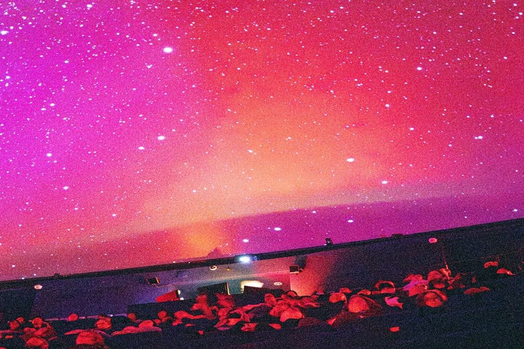 플라네타륨에서 화면을 보는 사람들의 무리