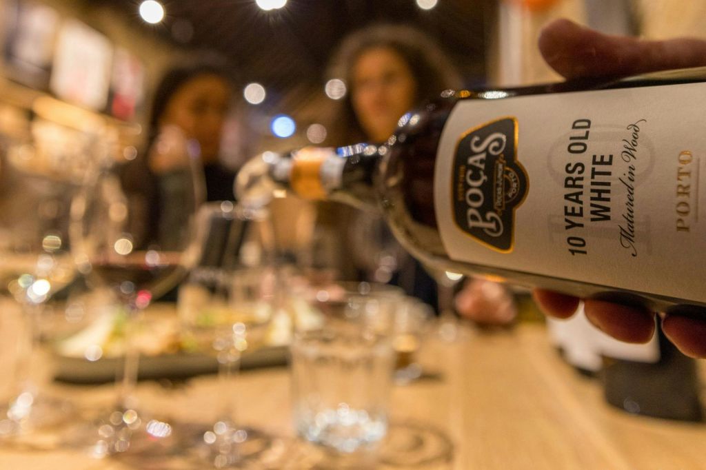 흐릿한 사람들과 테이블을 배경으로 "10 Years Old White" 라고 적힌 병을 클로즈업했습니다.