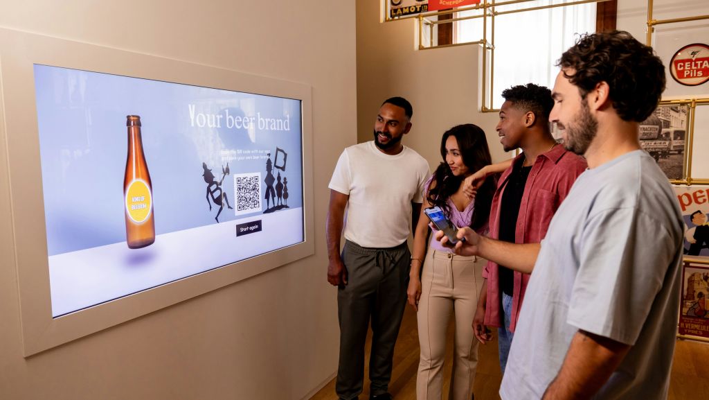 "발효의 종류" 및 "유럽의 교차로" 와 같은 다양한 주제를 표시하는 표지판이 있는 밝은 방을 걷는 사람들.