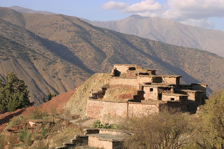 험준한 산악 지형을 배경으로 언덕에 버려진 오래된 석조 건물이 밀집해 있습니다.