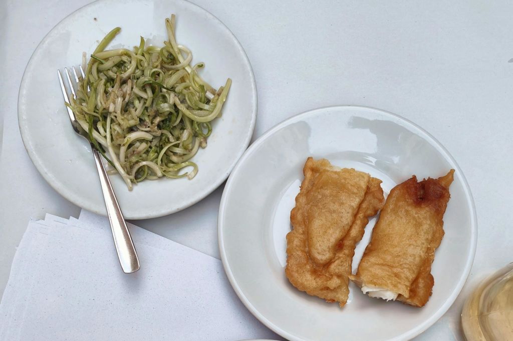 테이블 위에 접시 두 개, 하나는 애호박 국수와 포크, 다른 하나는 튀긴 음식 두 조각.